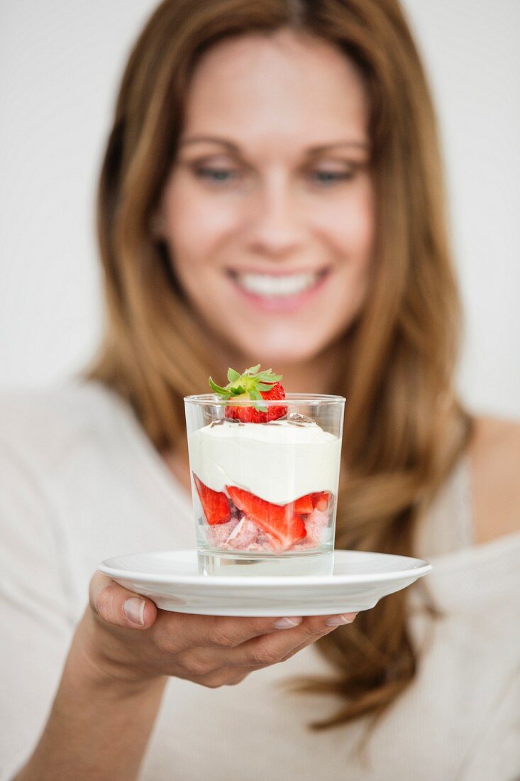 A woman holding a glass of strawberry tiramisu