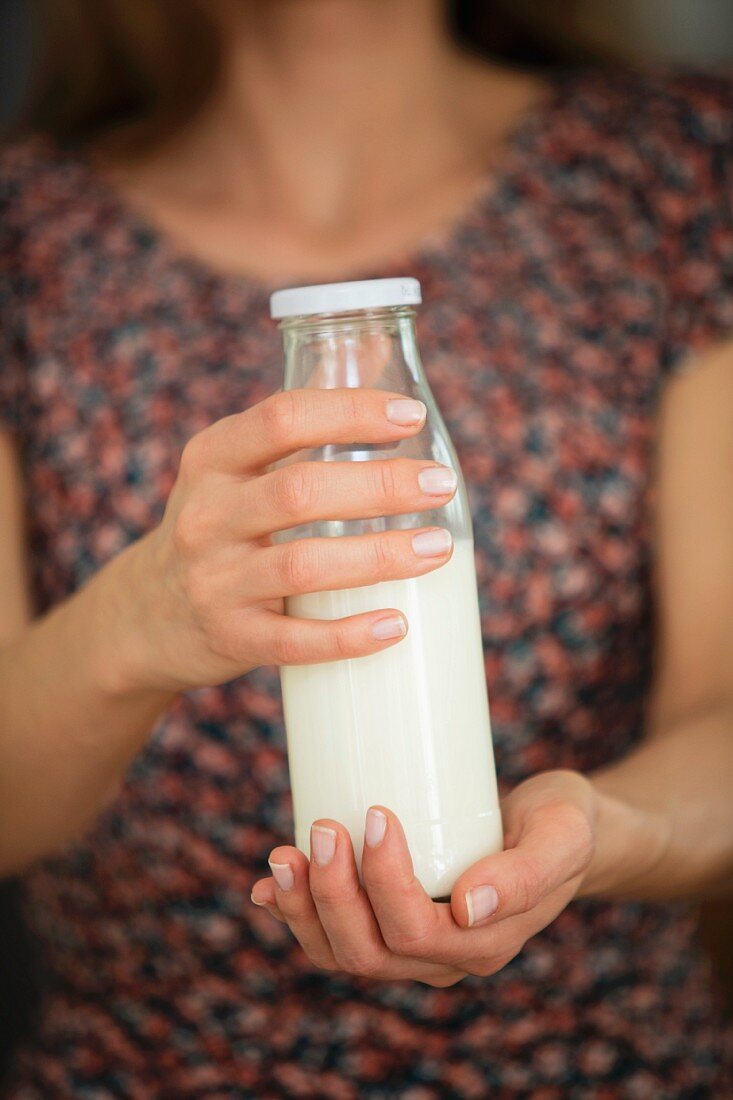 A woman holding a bottle of grain milk