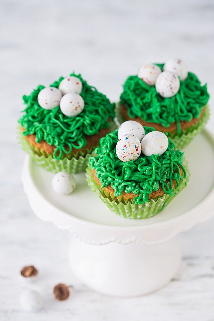 Easter cupcakes with green frosting and sugar eggs on a cake stand