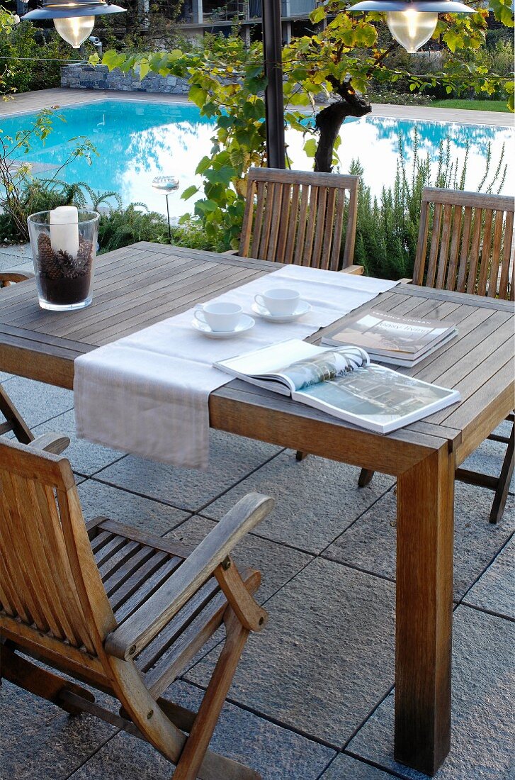 Wooden table and chairs on terrace next to pool