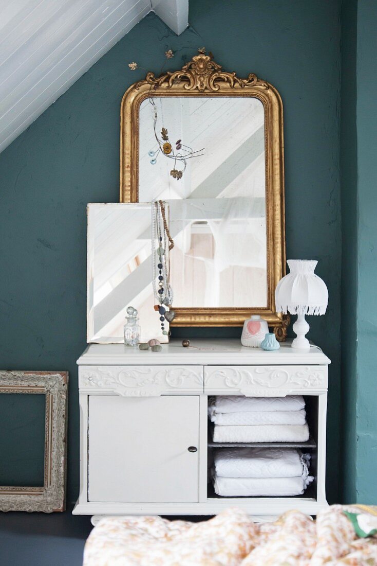 Antique gilt-framed mirror on top of old cabinet