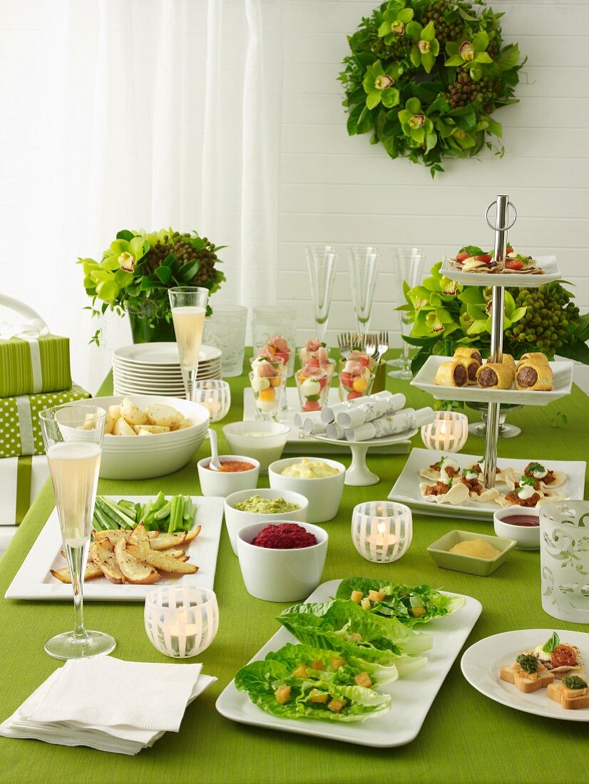 Christmas buffet on table with green tablecloth and green flower bouquets in glass vases