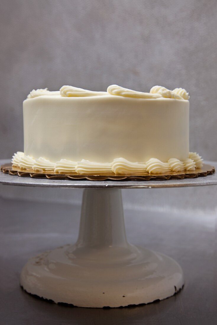 Ganze Schichttorte mit Buttercreme und Karamellpunkten auf Tortenständer