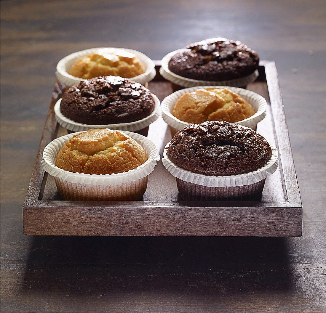 Various muffins on a wooden tray