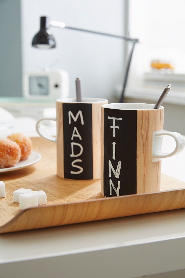 Wood-effect mugs with names written on chalkboard stripes