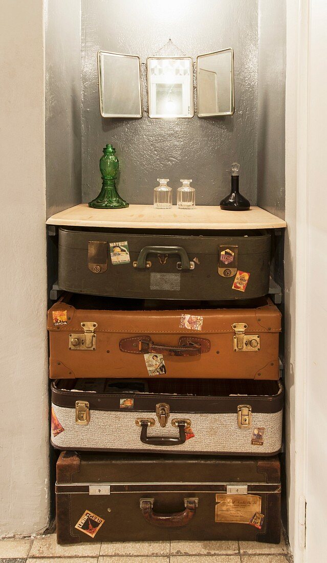 Vintage Kofferstapel in Wandnische mit verschiedenen Glasgefäßen
