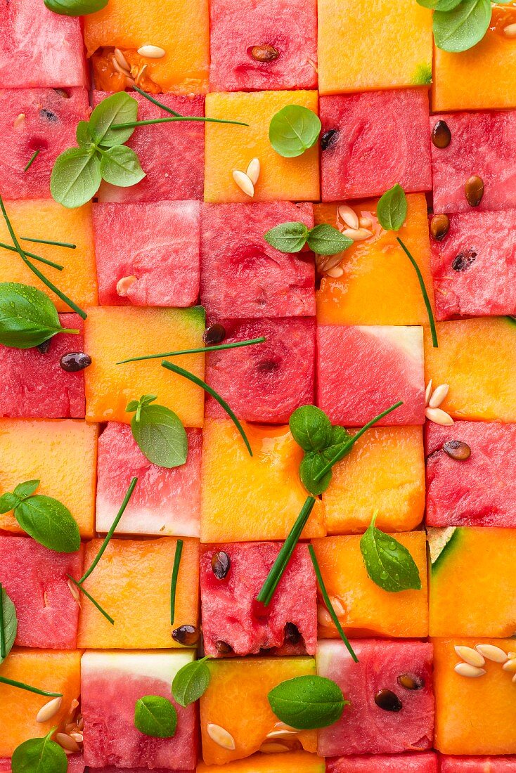 Pink and yellow diced melon with melon pips and basil leaves