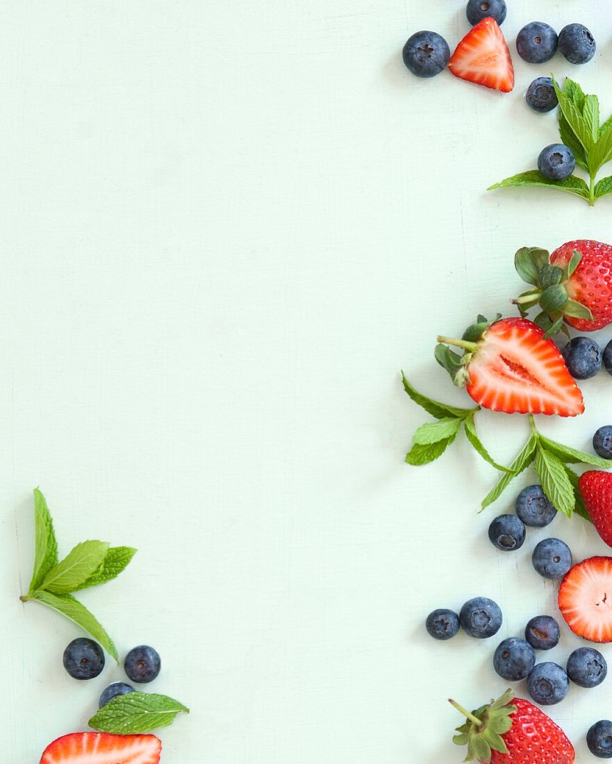 Fresh strawberries, blueberries and mint around the edge of the picture