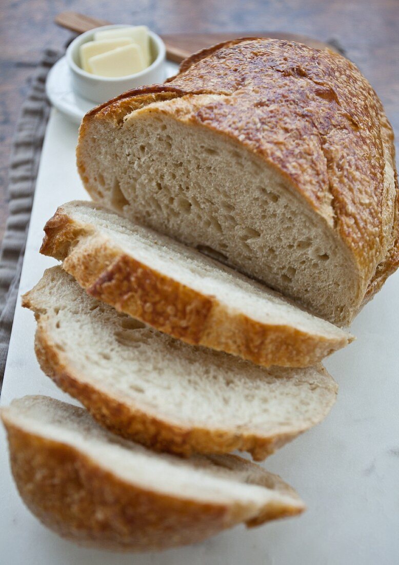 Brot mit abgeschnittenen Scheiben, Butter im Hintergrund