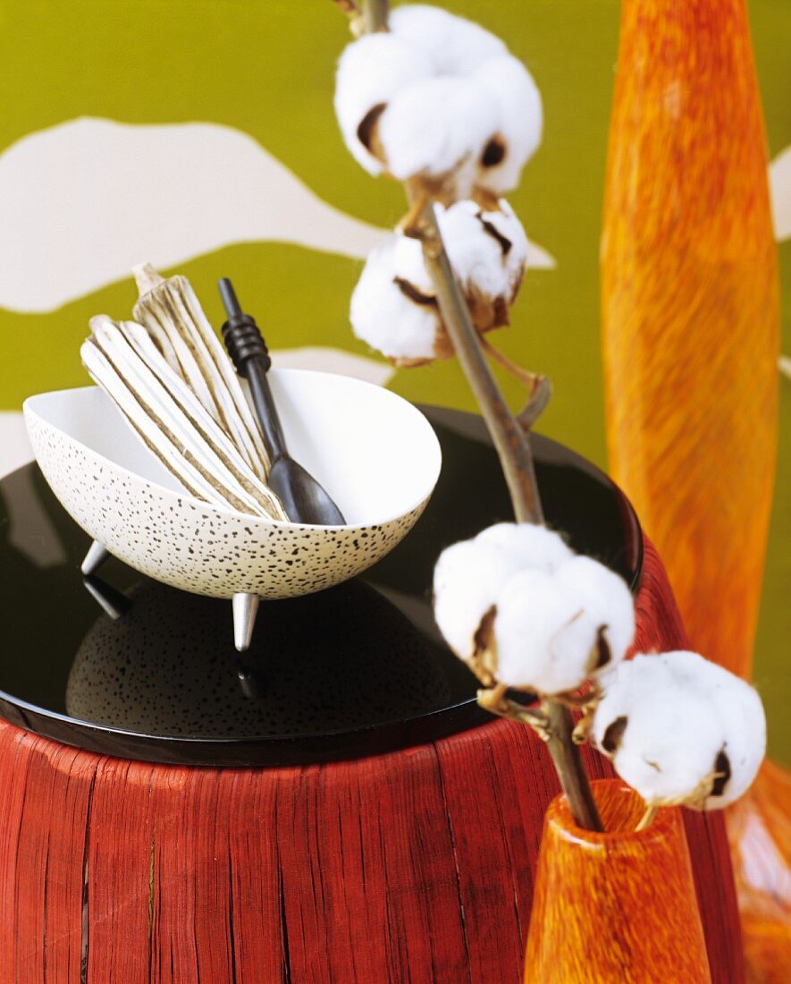 Twigs of cotton bolls in vase and ethnic ornaments in bowl