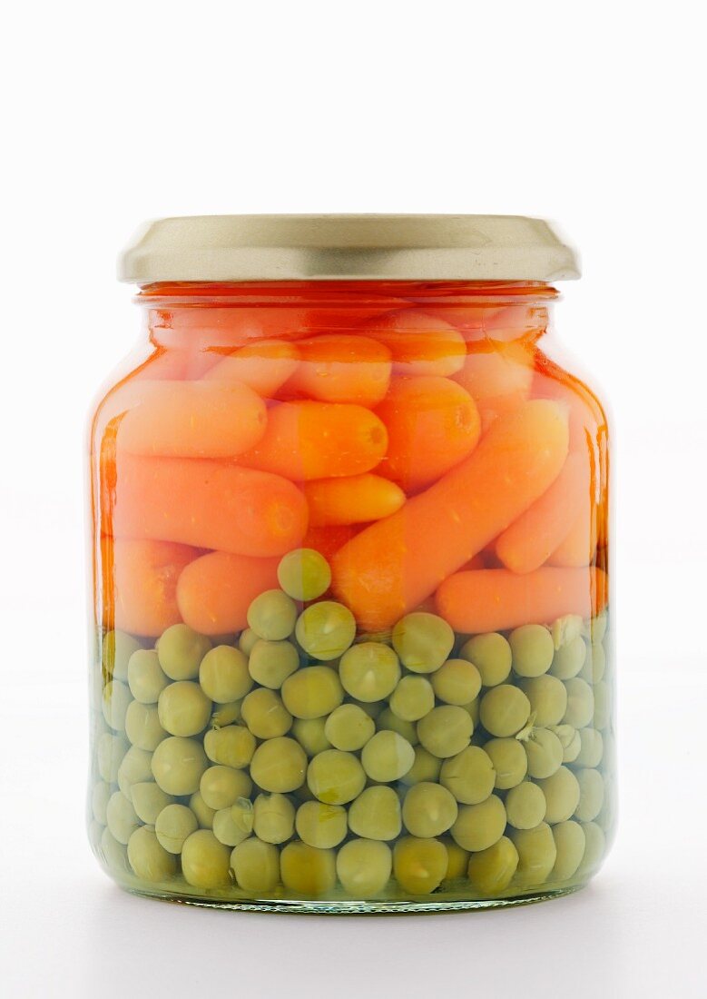 Peas and carrots in a jar on a white surface