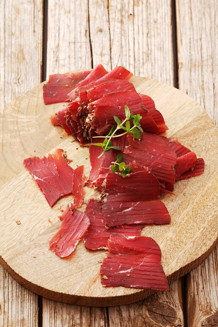 Sliced smoked beef on a wooden surface (South Tyrol)