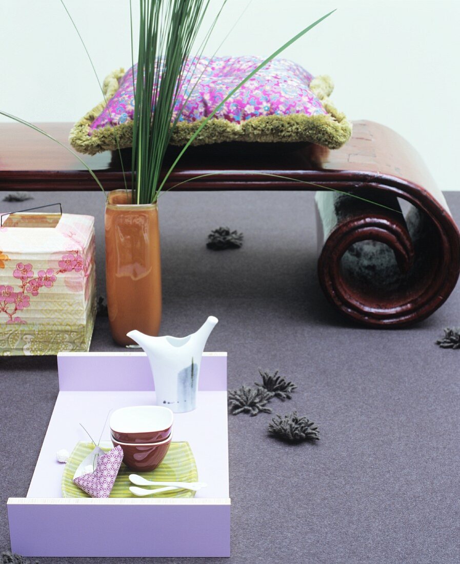 Tea service on modern tray in front of Oriental bench with spiral legs
