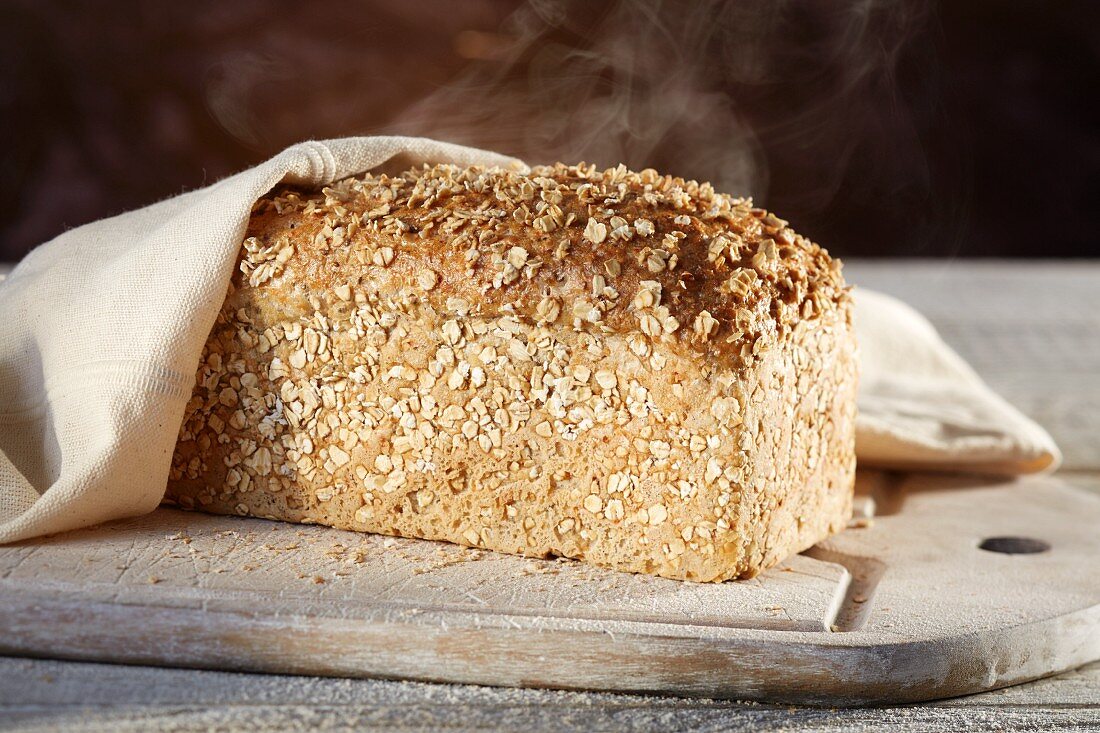 A steaming loaf of spelt-chia bread on a chopping board