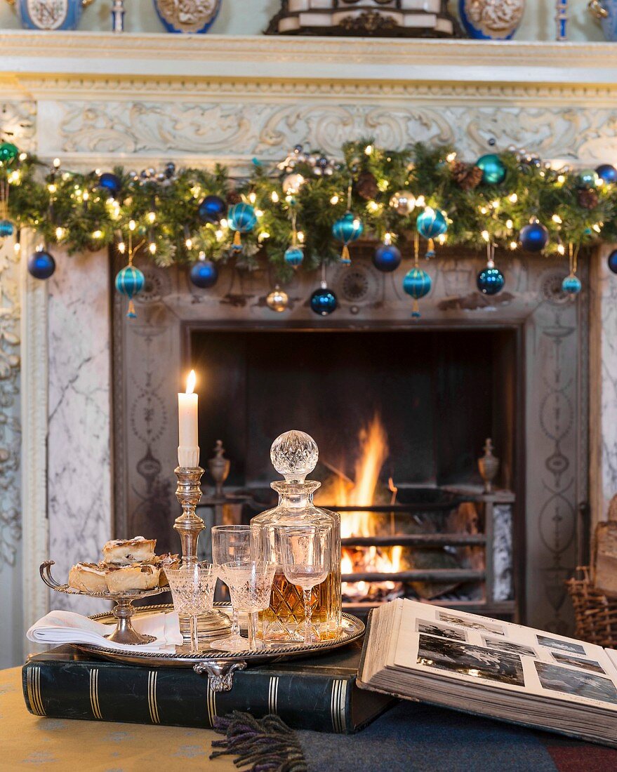 Tablett mit Whiskeykaraffe und Gläsern vor weihnachtlichem Kamin