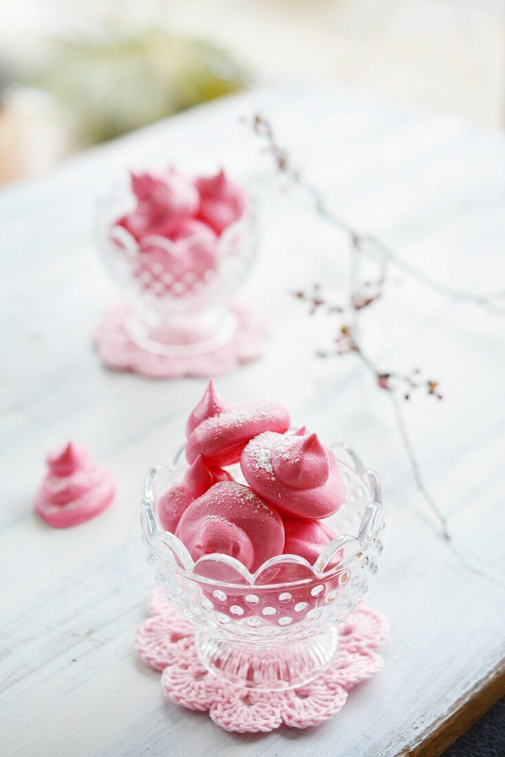 Pink meringues in glass bowls on an old table