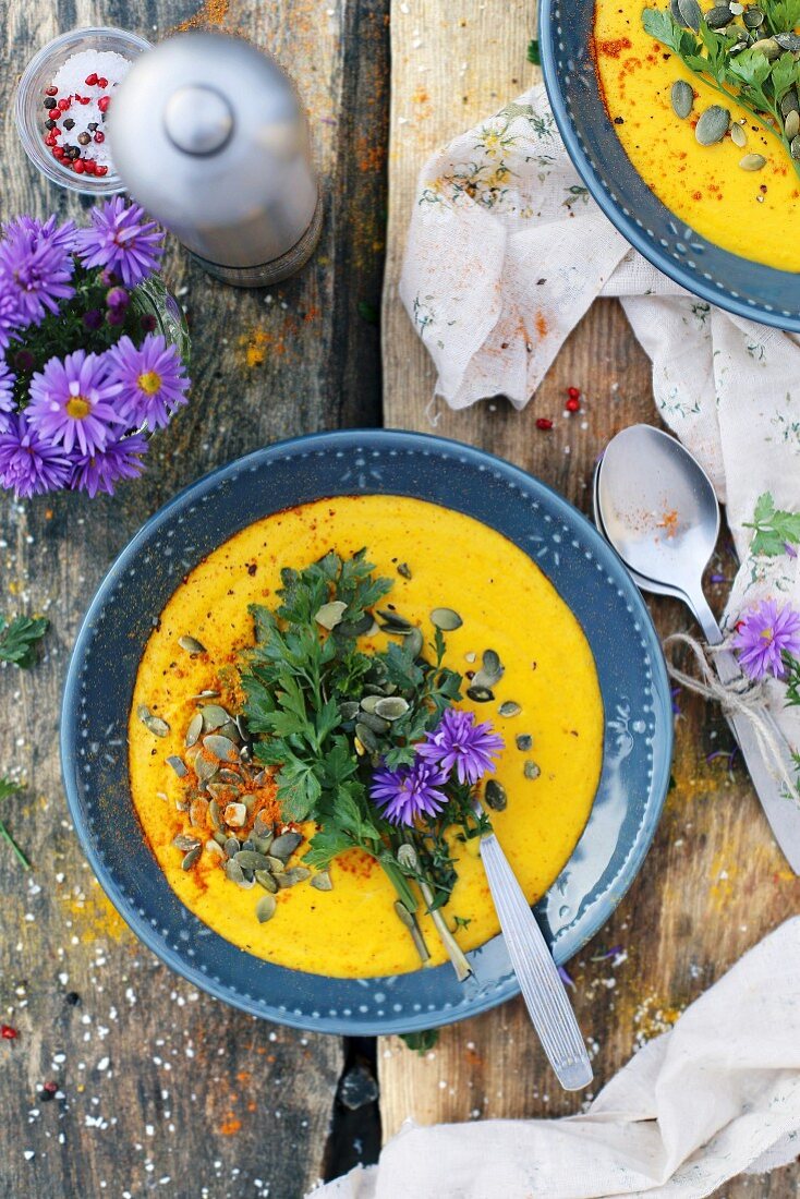 Cream of pumpkin soup with herbs and flowers on a wooden table