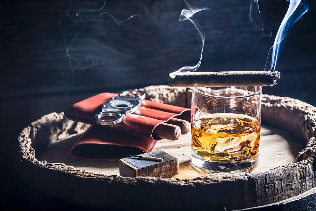 A smoking cigar over a glass of whiskey