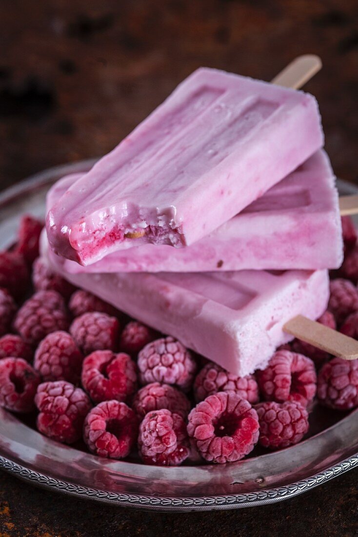 Raspberry cheesecake ice cream sticks with frozen raspberries on a silver tray