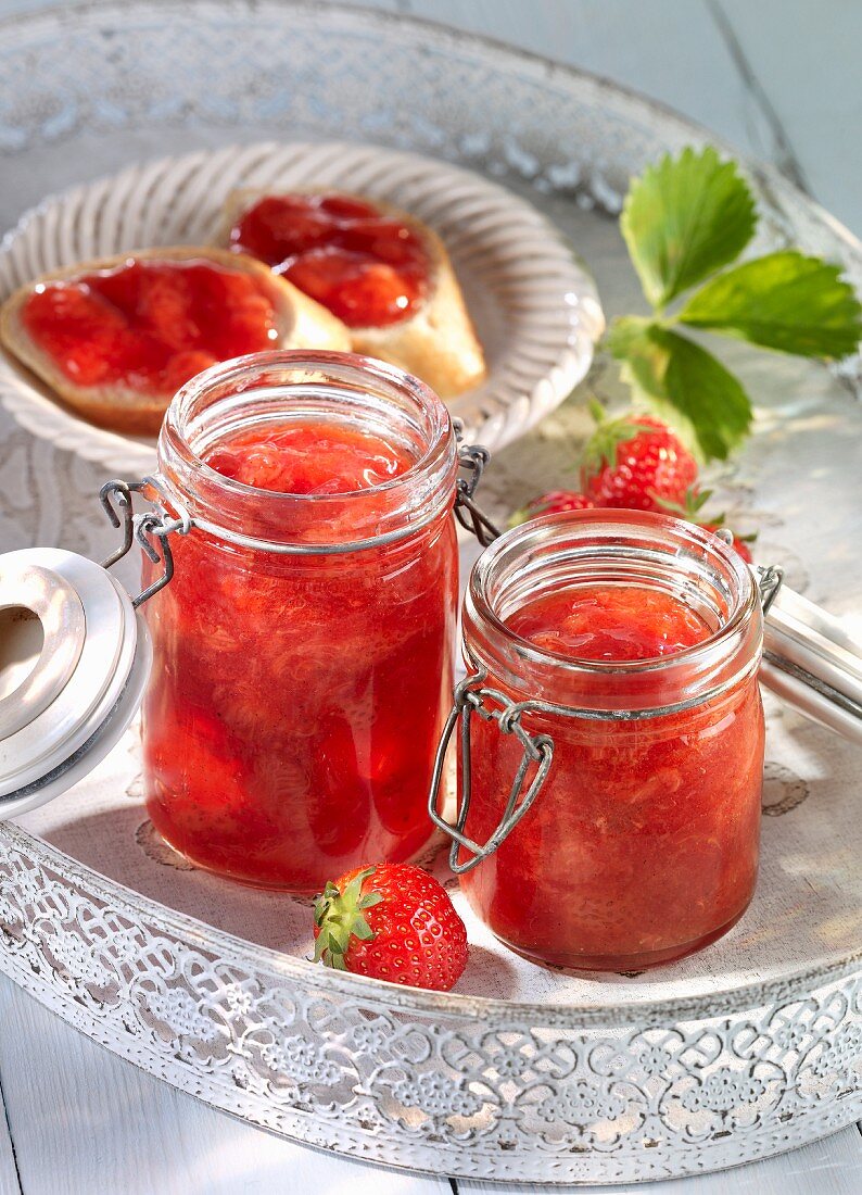 Strawberry jam in jars and on bread