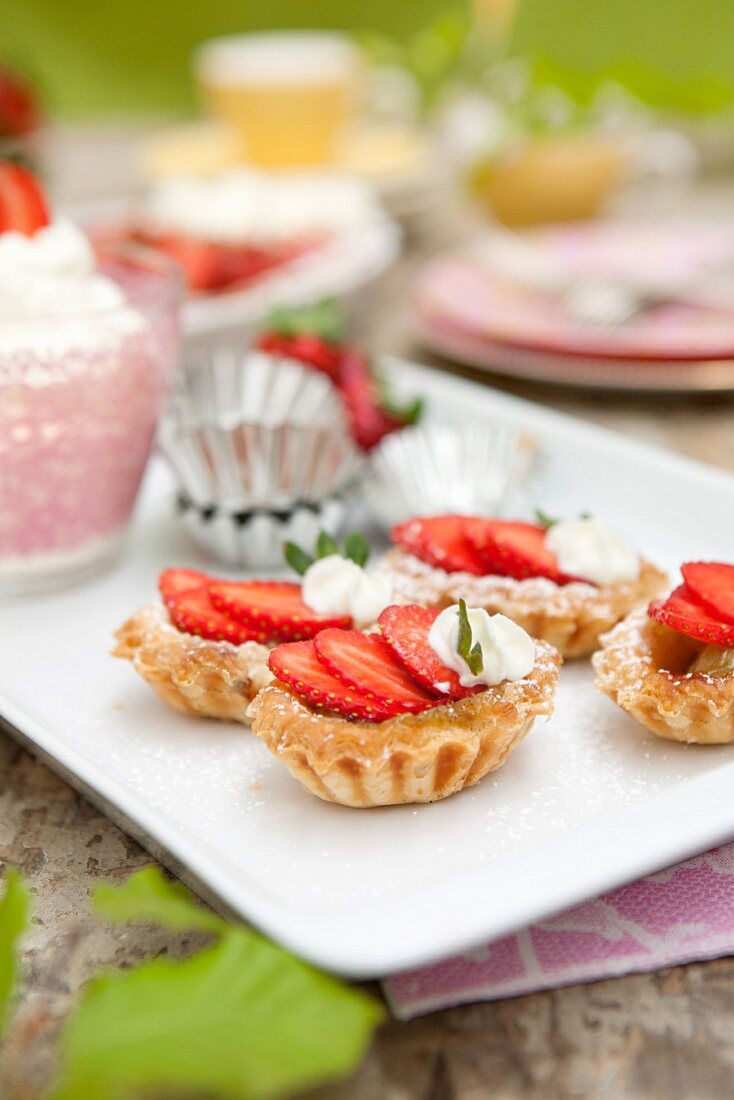 Strawberry tartlets with whipped cream and mint leaves