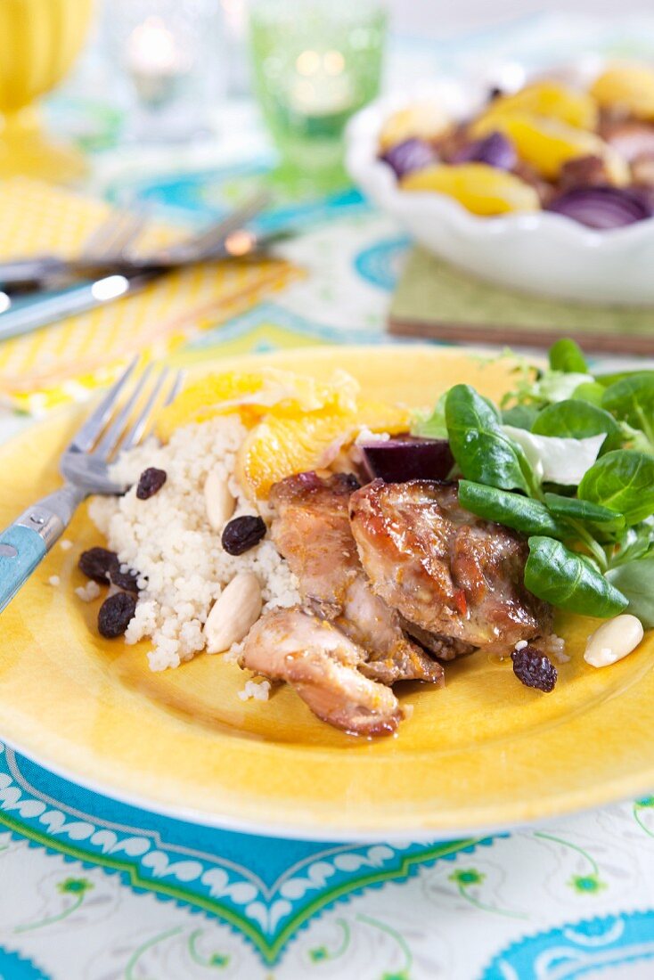 Chicken and couscous with raisins, almonds, red onions and orange salad
