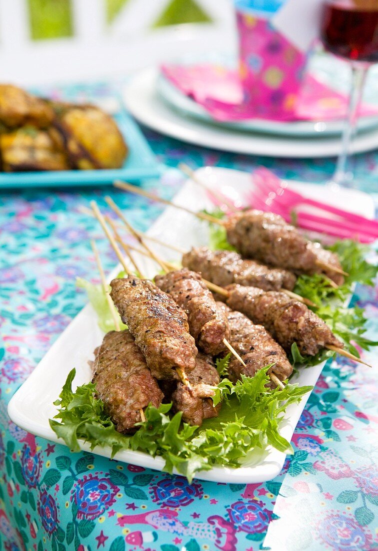 Grilled minced lamb skewers on a bed of lettuce
