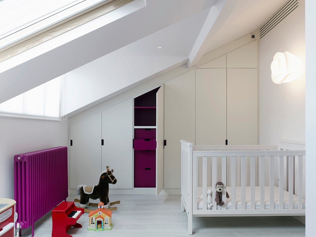 Attic nursery with fitted wardrobes under sloping ceiling