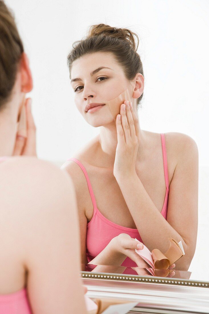 Woman patting powdered paper on face