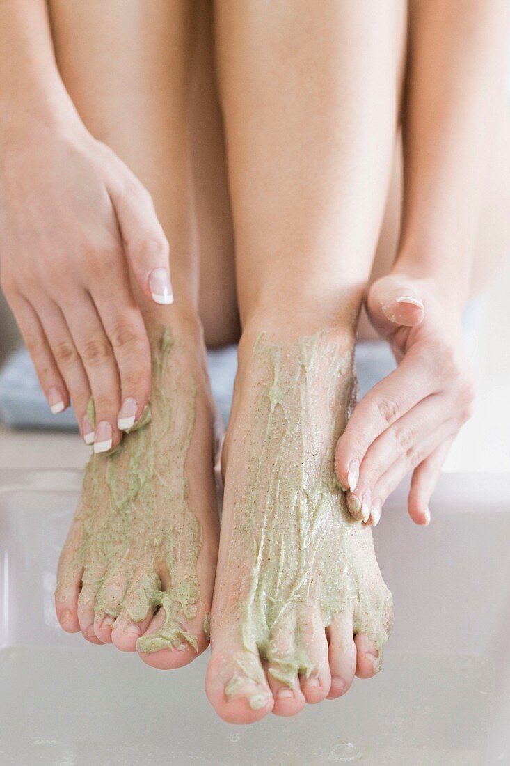 A woman applying and exfoliation treatment to her feet
