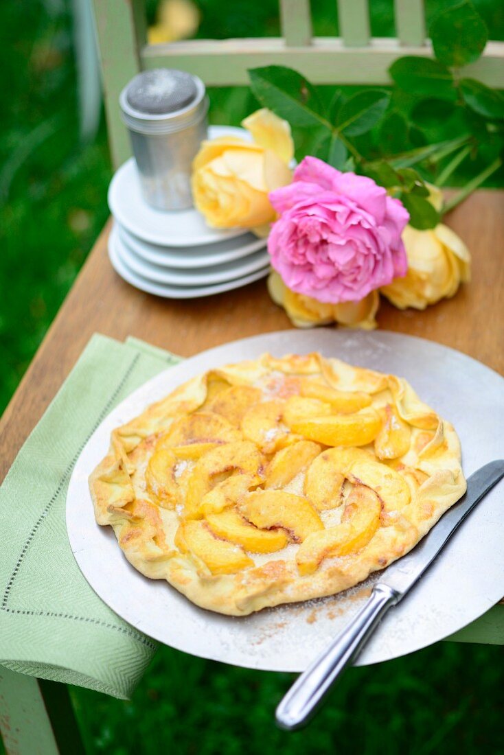 Galette with nectarines and peaches on a chair outside