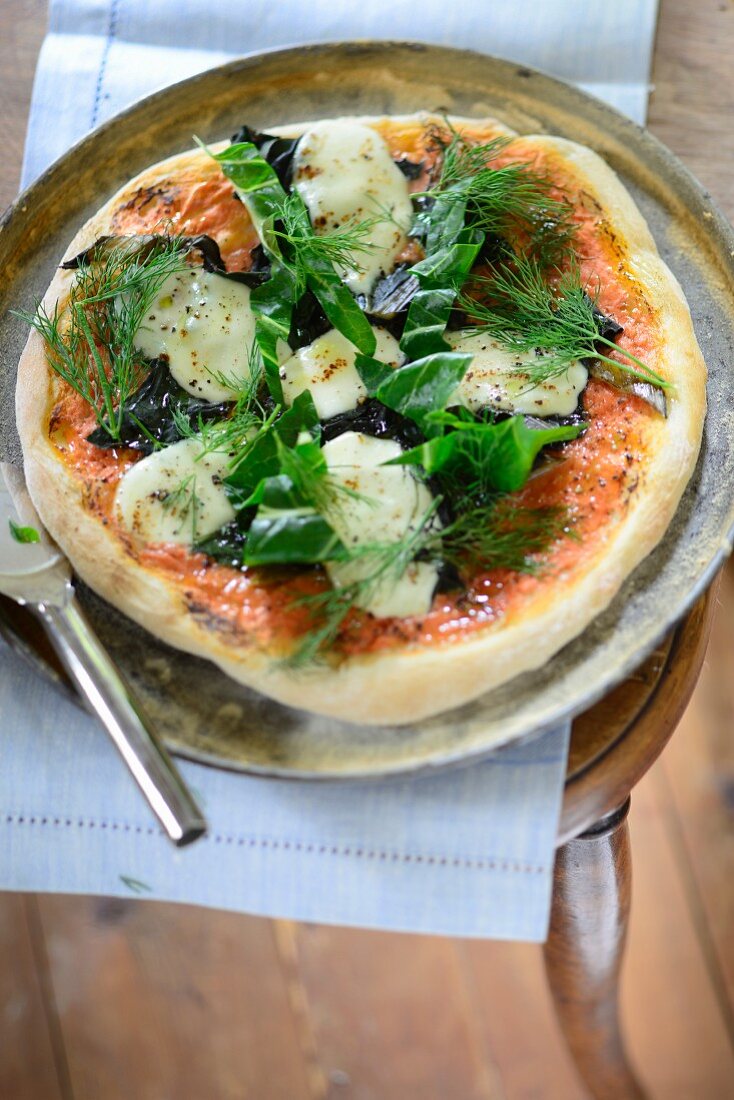 Pizza with braised green vegetables, mozzarella, tomatoes and dill oil