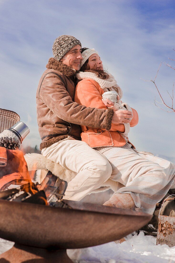 Man and woman cuddling during a winter picnic in a snowy landscape