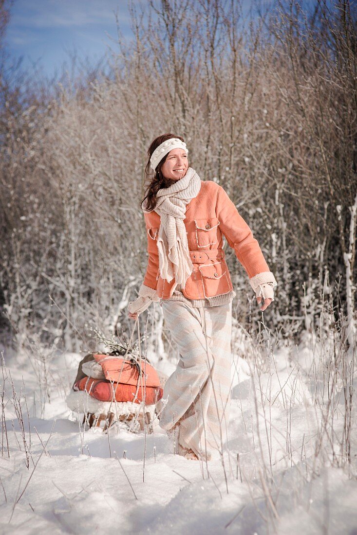 Frau zieht einen bepackten Schlitten durch Winterlandschaft