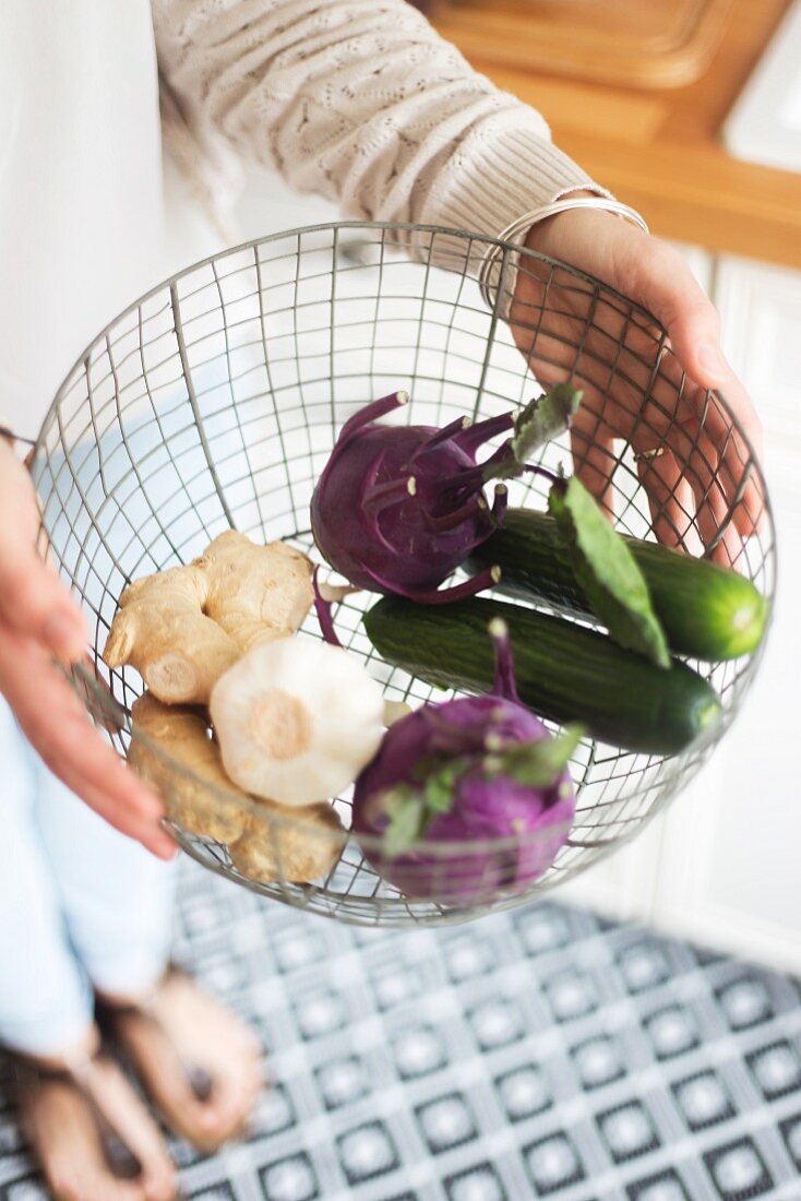 Wire basket of vegetables held in hands