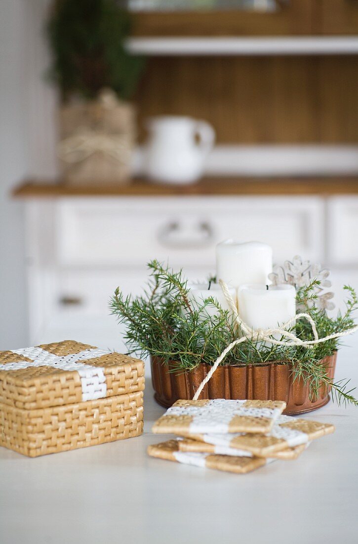 Painted seagrass coasters in front of Christmas arrangement in copper cake tin