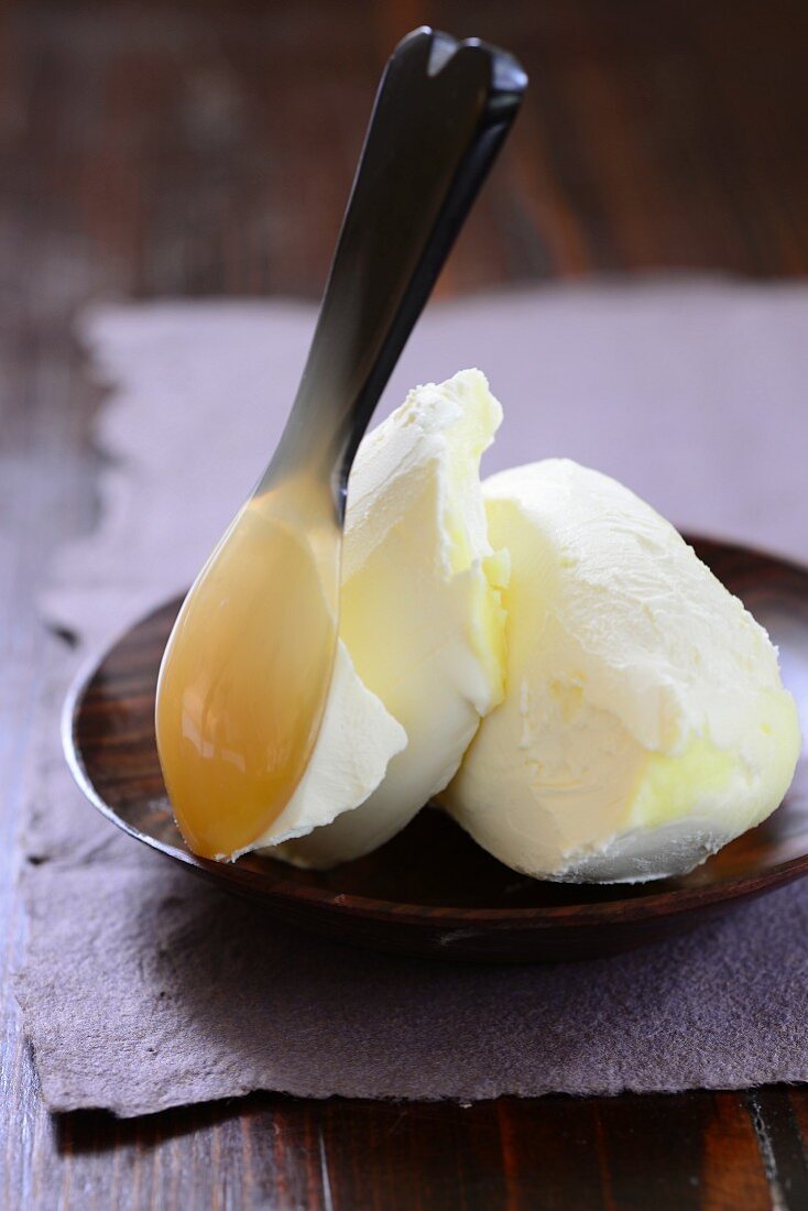 Lactose-free vegan margarine with a spoon on a wooden plate