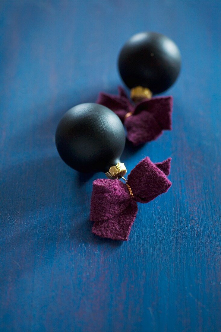 Black Christmas-tree baubles with felt ribbons