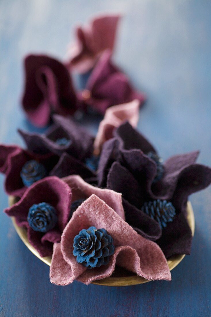 Blue-painted larch cones in folds of felt in berry shades