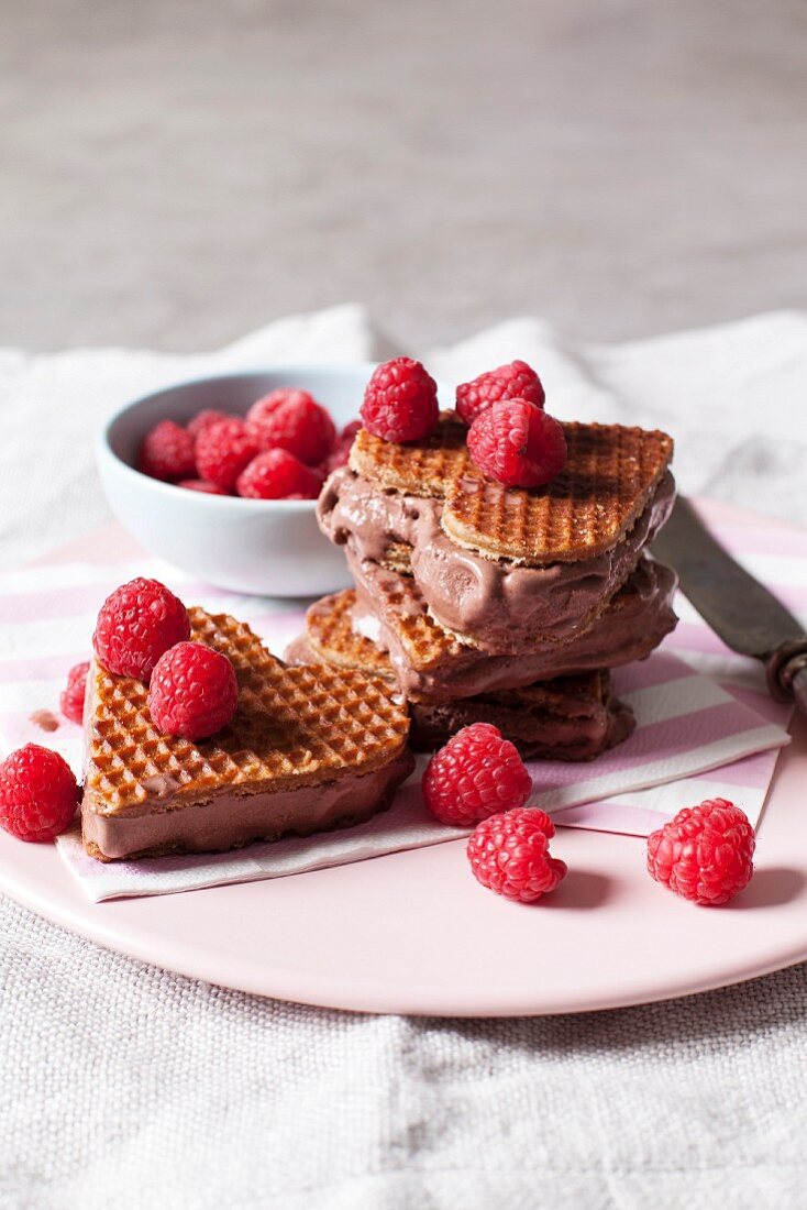 Heart-shaped ice cream sandwiches with stroopwaffels, chocolate ice cream and raspberries