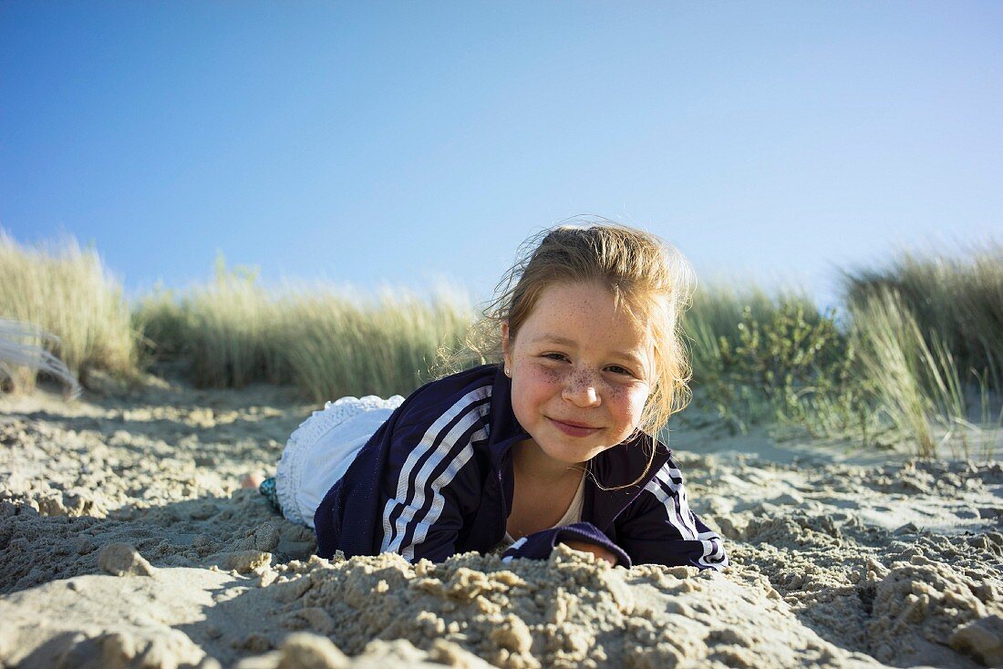 Young girl lying in sand