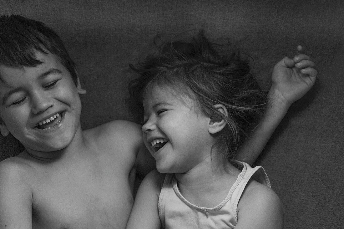 Bruder und Schwester lachen zusammen (s/w-Bild)