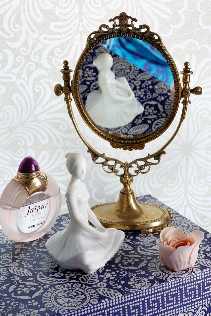 Feminine still-life arrangement of mirror, china figurine and perfume