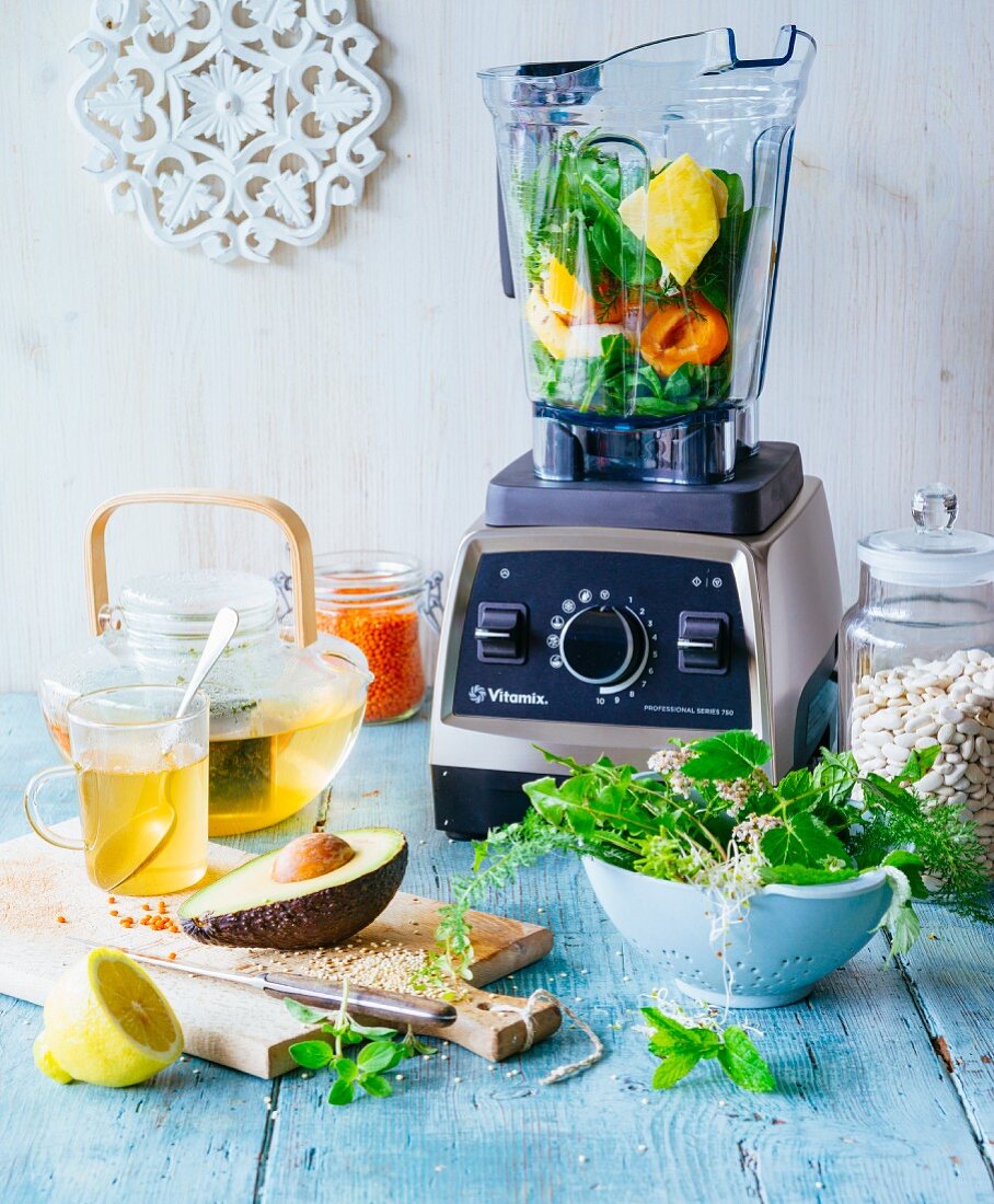 Ingredients for vegan fasting: a blender with fruit and vegetables, herb tea and herbs