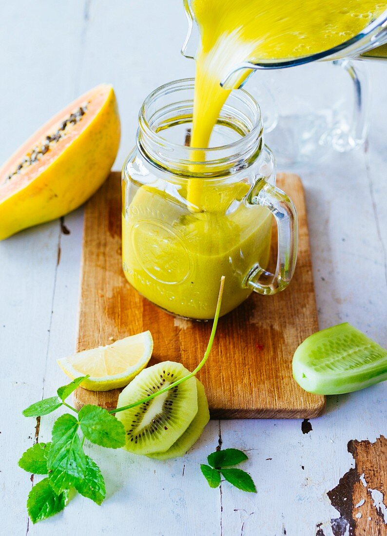 Gelber Smoothie mit exotischen Früchten, Gurke und Kräutern