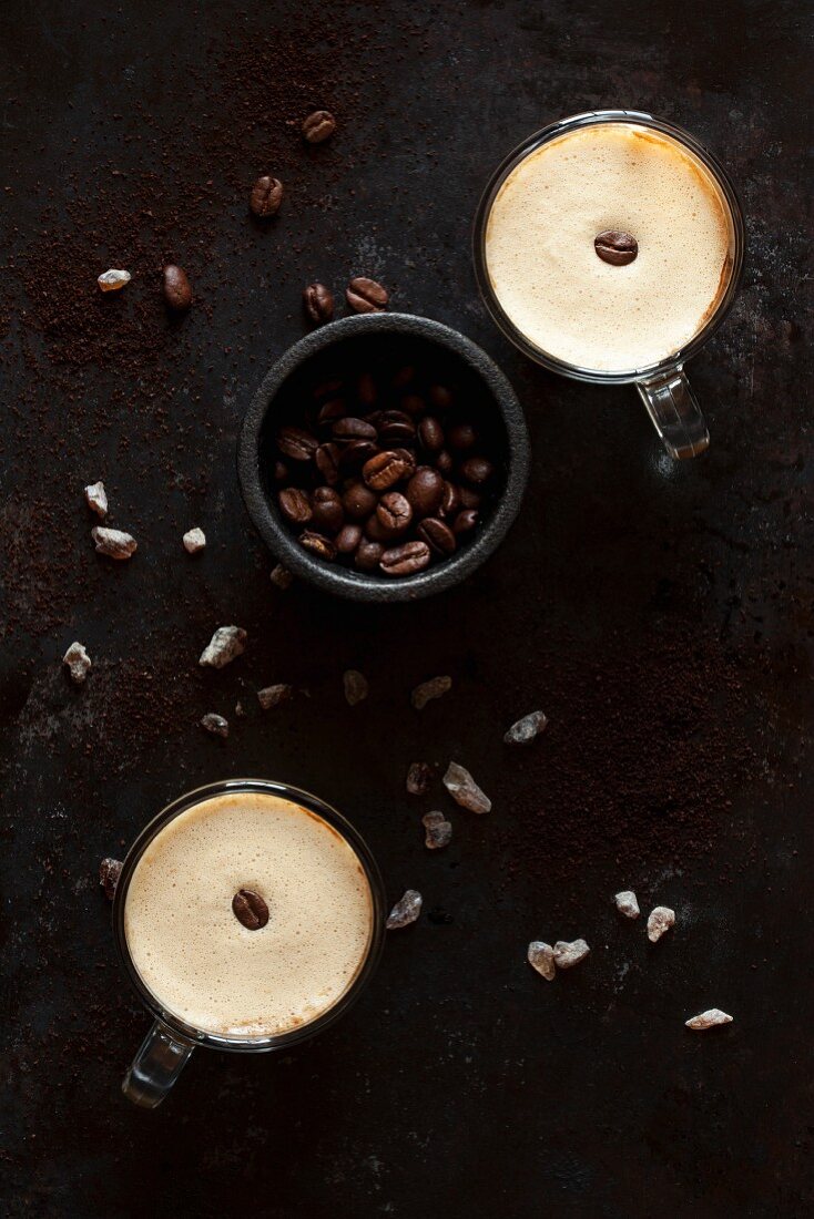 Schaumiger Kaffee mit Kaffeebohnen und braunem Kandiszucker
