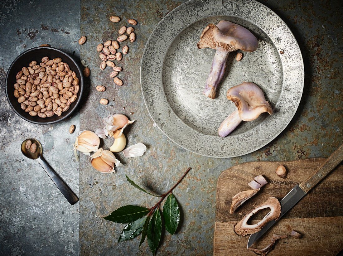 An arrangement of mushrooms, bay leaves, garlic and borlotti beans