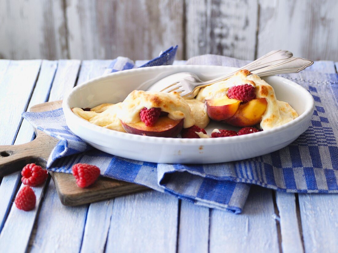 Baked peaches with raspberries in a baking dish