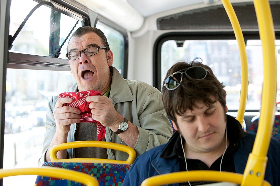 Man sneezing on public transport