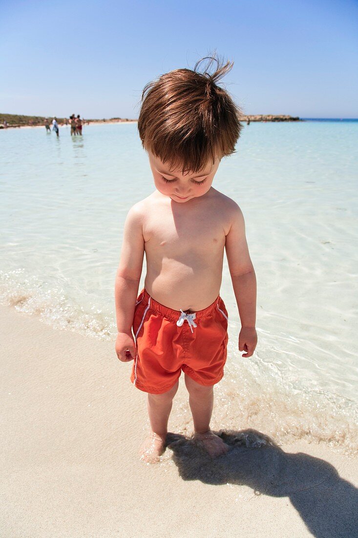 Boy testing the sea temperature with feet